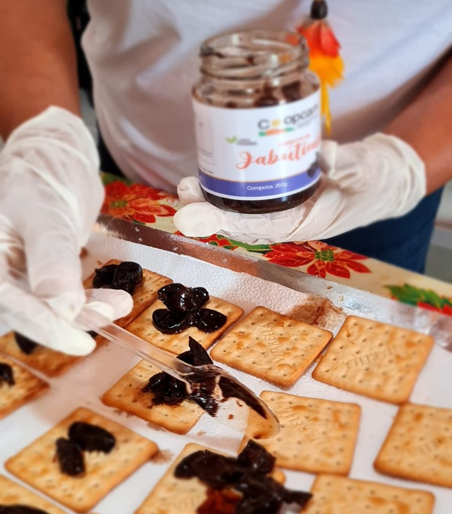 Mãos adicionando jabuticaba em bolachas salgadas em rota de turismo sustentável no Nordeste